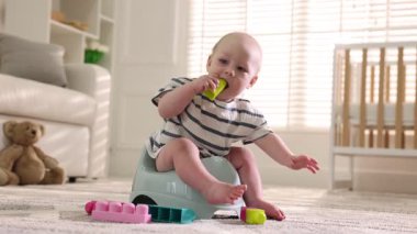 Evdeki lazımlık ve oyuncaklar üzerinde oturan tatlı küçük bebek.