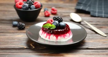 Lezzetli panna cotta, böğürtlenli ve nane şekerli, ahşap masa, yakın plan. Kamera yakınlaştırılıyor