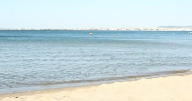 Güzel dalgalı deniz ve kumlu sahil, kameralar yakınlaşıyor.