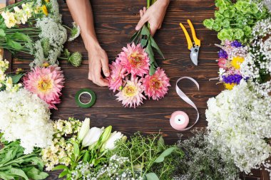 Ahşap masada çiçek buketi yapan profesyonel bir çiçekçi.
