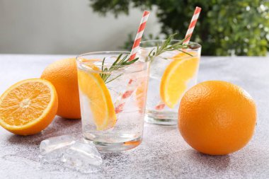 Portakal dilimli maden suyu ve gri masada biberiye, yakın plan.