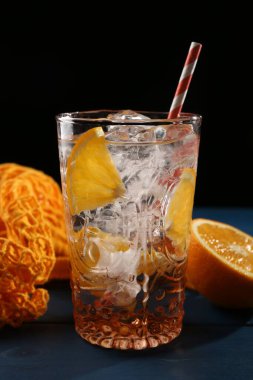 Bardakta portakallı köpüklü su ve mavi ahşap masada taze meyveler, yakın plan.