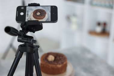Stüdyoda akıllı telefonla çikolatalı pasta çekmek, seçici odaklanma. Profesyonel yemek fotoğrafçılığı.