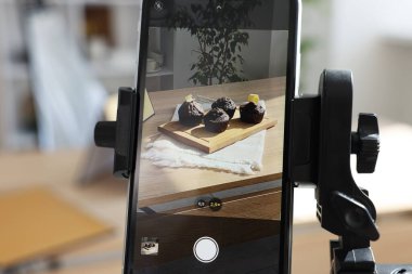 Stüdyoda akıllı telefonlu çikolatalı kek çekmek, seçici odaklanma. Profesyonel yemek fotoğrafçılığı.