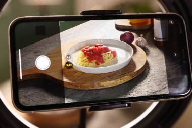 Stüdyoda akıllı telefonlu lezzetli makarna ve malzemeler çekmek, seçici odaklanma. Profesyonel yemek fotoğrafçılığı.