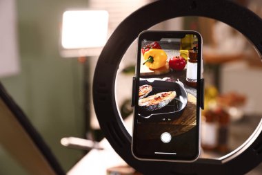 Stüdyoda lezzetli kızarmış balık ve akıllı telefonlu malzemeler çekmek, seçici odaklanma. Profesyonel yemek fotoğrafçılığı.