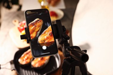 Stüdyoda akıllı telefonlu lezzetli kızarmış balık çekmek, seçici bir odak noktası. Profesyonel yemek fotoğrafçılığı.