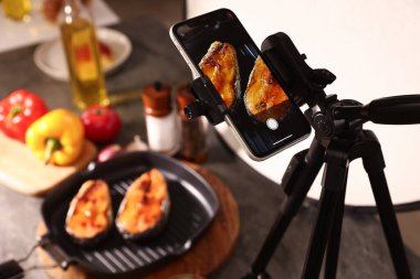 Stüdyoda akıllı telefonlu lezzetli kızarmış balık çekmek, seçici bir odak noktası. Profesyonel yemek fotoğrafçılığı.
