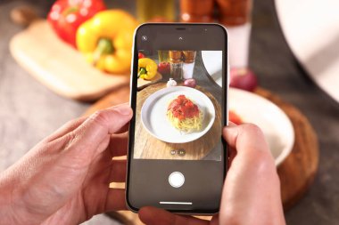 Stüdyoda lezzetli makarna ve malzemelerin fotoğrafını çeken kadın, seçici odaklanma. Profesyonel yemek fotoğrafçılığı.