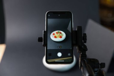 Stüdyoda akıllı telefonla lezzetli makarna çekmek, ekrana odaklanmak. Profesyonel yemek fotoğrafçılığı.
