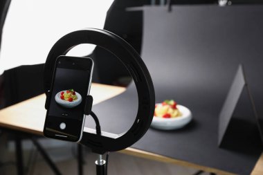 Stüdyoda akıllı telefonla lezzetli makarna çekmek, ekrana odaklanmak. Profesyonel yemek fotoğrafçılığı.