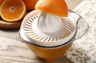 Meyve suyu. Meyve sıkacağı ve taze portakallar ahşap masada, yakın plan.