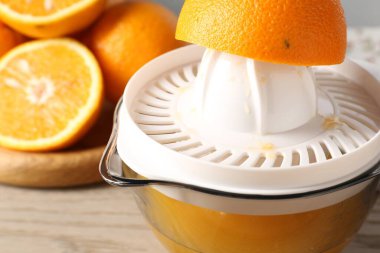 Meyve suyu. Meyve sıkacağı ve taze portakallar ahşap masada, yakın plan.