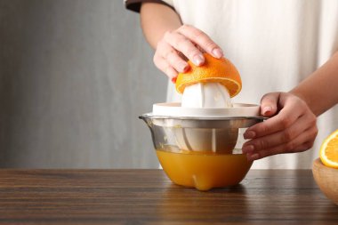 Meyve suyu. Tahta masada portakal suyu kullanan kadın, yakın plan. Metin için boşluk