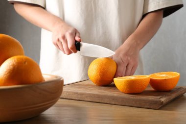 Meyve suyu. Ahşap masada turuncu kesen kadın, yakın plan.