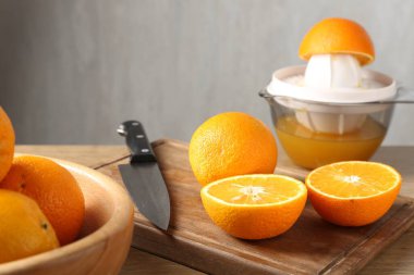 Meyve suyu. Taze portakallar, meyve sıkacağı ve bıçak ahşap masada, yakın plan.