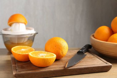 Meyve suyu. Meyve sıkacağı, taze portakal ve bıçak ahşap masada, yakın plan.