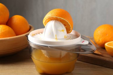 Meyve suyu. Meyve sıkacağı ve taze portakallar ahşap masada, yakın plan.