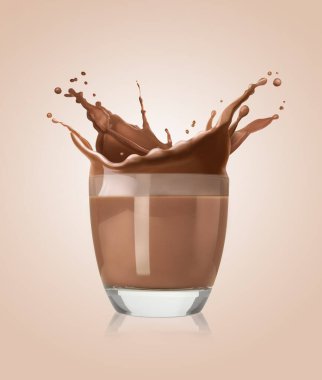 Bej renkli arkaplanda bardağa dökülen çikolatalı süt.