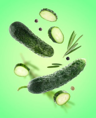 Taze salatalıklar, biberiye ve biber taneleri açık yeşil arka plana düşüyor.