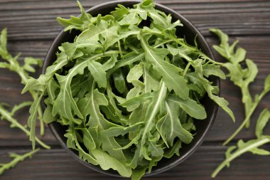 Taze yeşil roka yaprakları koyu ahşap masada, düz yerde.