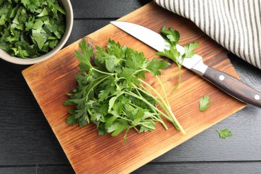 Taze aromalı maydanoz ve bıçak siyah ahşap masada, düz yatıyordu.