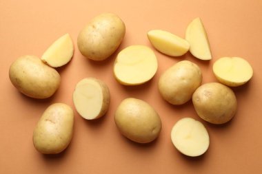 Açık kahverengi arka planda taze çiğ patates, düz uzanmış.