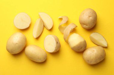 Sarı arka planda taze çiğ patates, düz uzanmış.