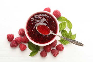 Tatlı ahududu reçeli kasede, böğürtlen ve yeşil yapraklar beyaz ahşap masada, düz yerde