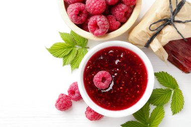 Tatlı ahududu reçeli, böğürtlen ve yeşil yapraklar beyaz ahşap masada, düz yatıyordu. Metin için boşluk