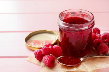 Cam kavanozda tatlı ahududu reçeli ve pembe ahşap masada böğürtlen, yakın plan. Metin için boşluk