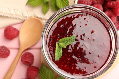 Tatlı ahududu reçeli cam kavanozda, böğürtlen ve nane şekeri pembe ahşap masada, düz yerde