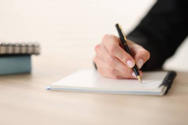 Kalemle tahta masada arka planda yazan kadın, yakın plan.