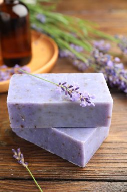 Sabun barları, diğer kozmetik ürünler ve lavanta çiçekleri ahşap masada, yakın plan.