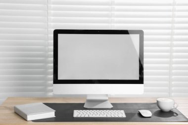 Kapalı alandaki ahşap masa üzerinde bilgisayar ve siyah fare altlığı olan şık bir iş yeri. Metin için boşluk