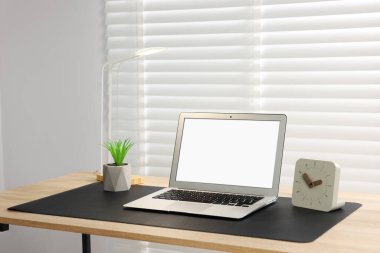 İç mekandaki ahşap masada dizüstü bilgisayarı ve siyah bir fare altlığı olan şık bir iş yeri. Metin için boşluk