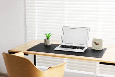 İç mekandaki ahşap masada dizüstü bilgisayarı ve siyah bir fare altlığı olan şık bir iş yeri. Metin için boşluk