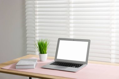 İçerideki ahşap masada dizüstü bilgisayarı ve pembe faresi olan şık bir iş yeri. Metin için boşluk