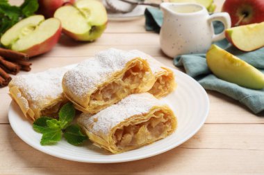 Lezzetli elmalı turta parçaları pudra şekerli ve nane şekerli, ahşap masa, yakın plan.