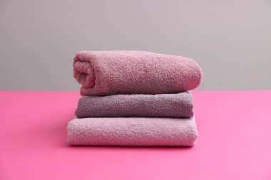 Pembe masadaki yumuşak havlu yığını gri arka plana karşı, yakın plan