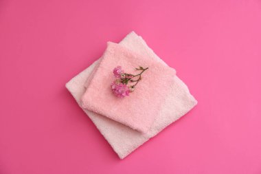 Yumuşak havlular ve pembe arka planda çiçekler, üst manzara.