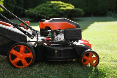 Bahçedeki yeşil çimlerin üzerinde bir çim biçme makinesi, yakın plan.