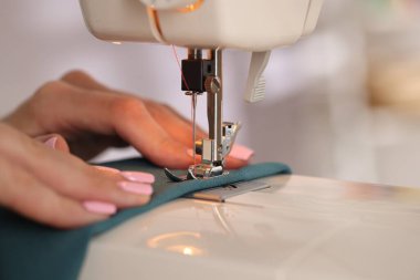 Atölyede dikiş makinesi ve kumaşla çalışan bir kadın.