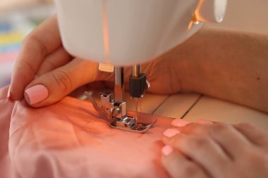 Atölyede dikiş makinesi ve kumaşla çalışan bir kadın.