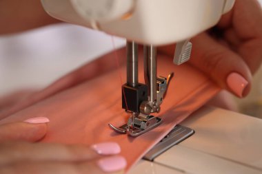 Atölyede dikiş makinesi ve kumaşla çalışan bir kadın.