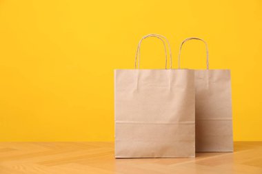 Turuncu arkaplana karşı ahşap masada iki kese kâğıdı torbası, mesaj için yer