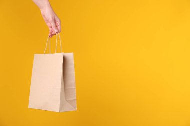 Turuncu arka planda kese kağıdı olan kadın, yakın plan. Metin için boşluk