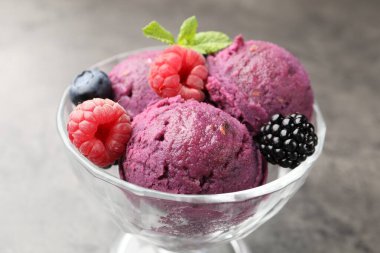 Taze böğürtlenli lezzetli şerbet ve tatlı kasesinde nane şekeri. Gri desenli masa, yakın plan.