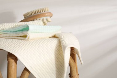 Waffle havluları ve hasır koltukta masaj fırçası, ışık duvarının yanında, yakın plan.