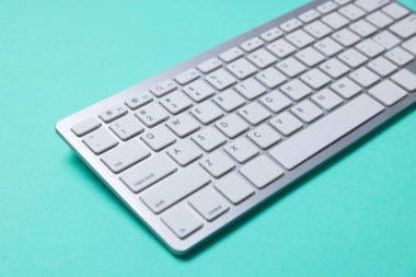 Turkuaz arka planda modern kablosuz bilgisayar klavyesi, yakın plan